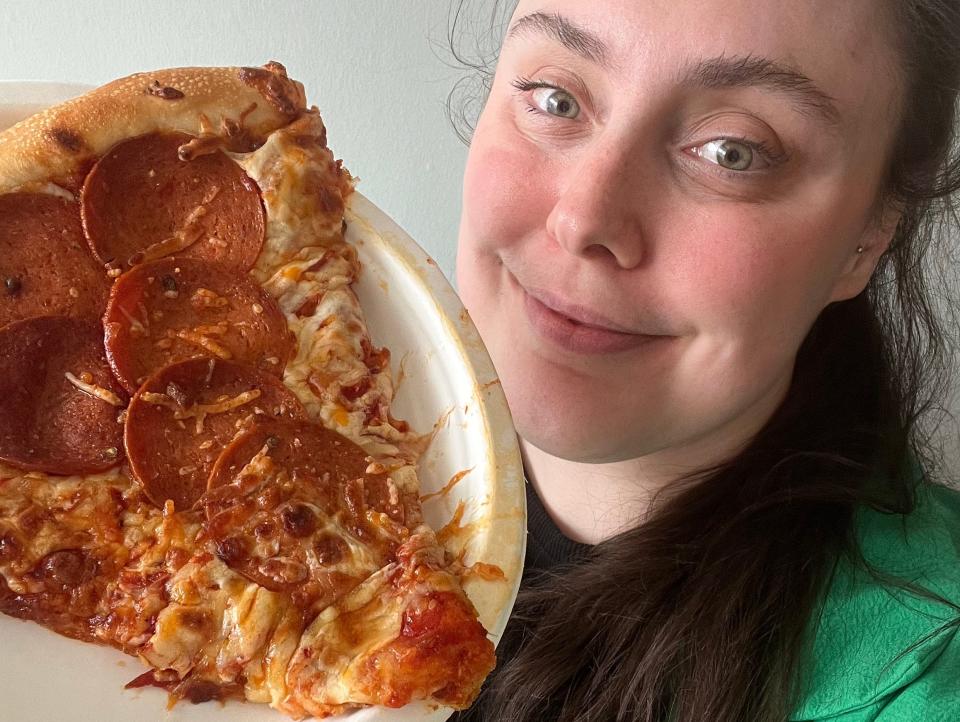 Selfie of the writer with a slice of pepperoni pizza