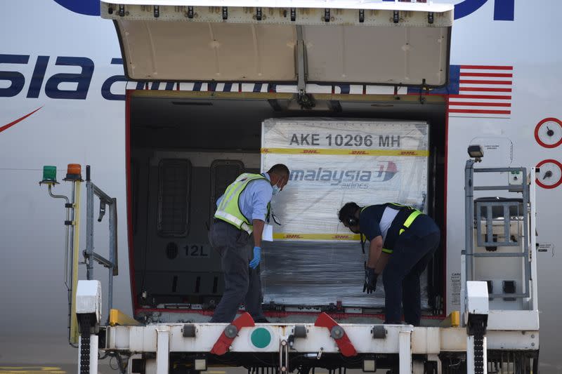 Containers carrying the first batch of Pfizer-BioNTech COVID-19 vaccines are unloaded from a plane at the MASkargo Complex in Sepang