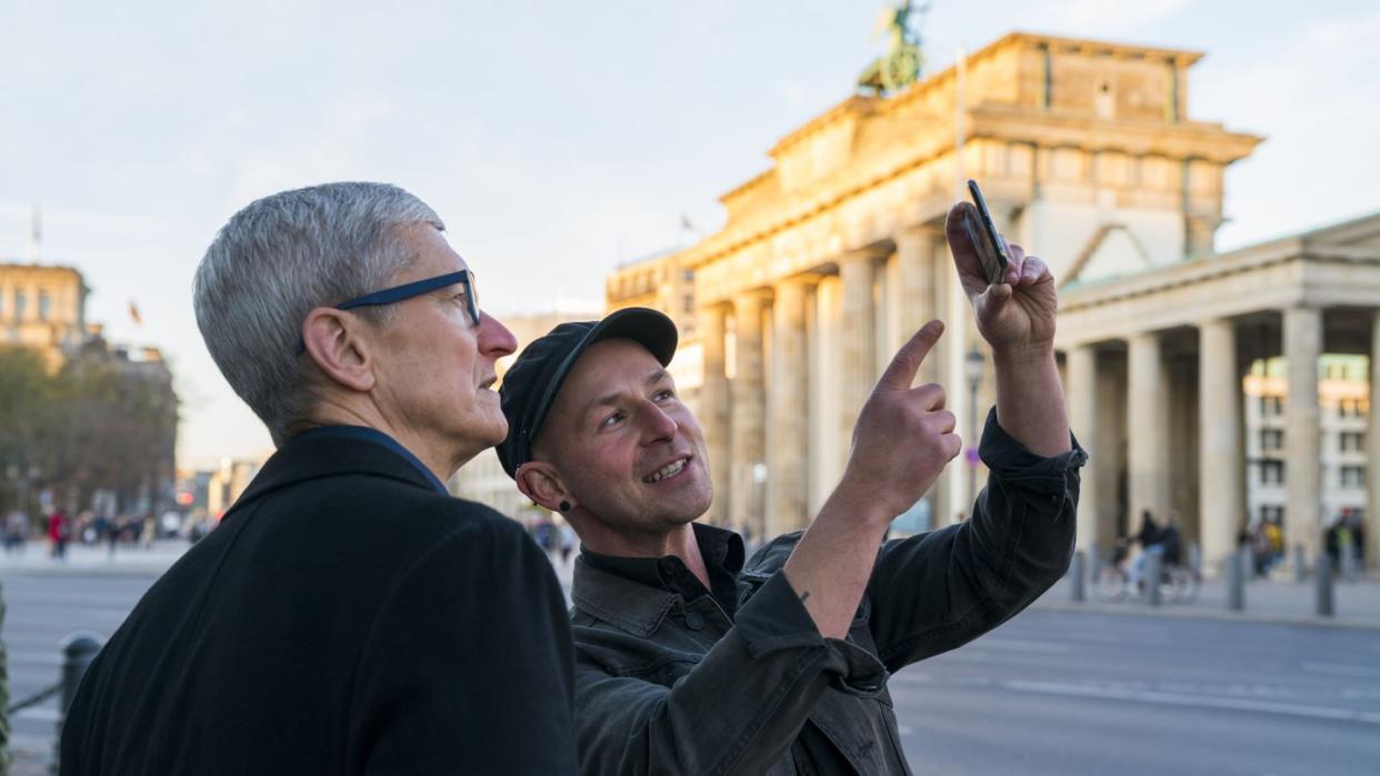 Apple-Chef Tim Cook (l) lässt sich am Brandenburger Tor von Entwickler Peter Kolski das Projekt «MauAR» erklären. Foto: Brooks Kraft/Apple