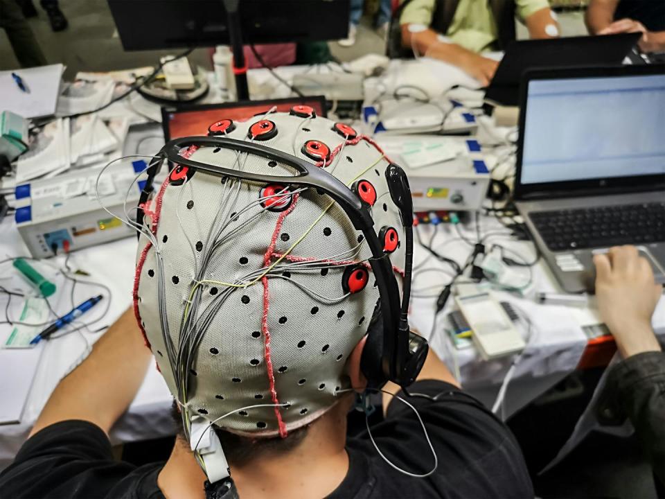 Persoon die een hersencomputerinterface gebruikt en een EEG-kap draagt ​​die is aangesloten op een laptop
