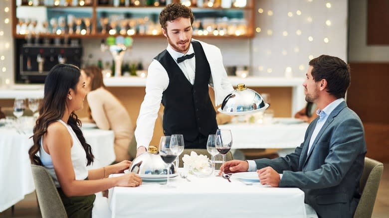 Waiter serving couple