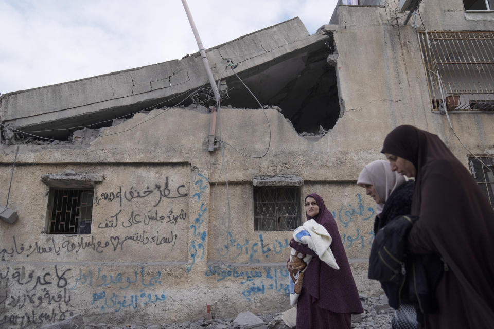 Palestinian women walk past a house that was demolished by the Israeli army in the West Bank village of Kafr Dan, near Jenin, Monday, Jan. 2, 2023. Palestinians Samer Houshiyeh and Fouad Abed were shot and killed during clashes with the Israeli army in the village of Kafr Dan near the northern city of Jenin. The Israeli military said it entered Kafr Dan late Sunday to demolish the houses of two Palestinian gunmen who killed an Israeli soldier during a firefight in September. The military said troops came under heavy fire and fired back at the shooters. (AP Photo/Nasser Nasser)