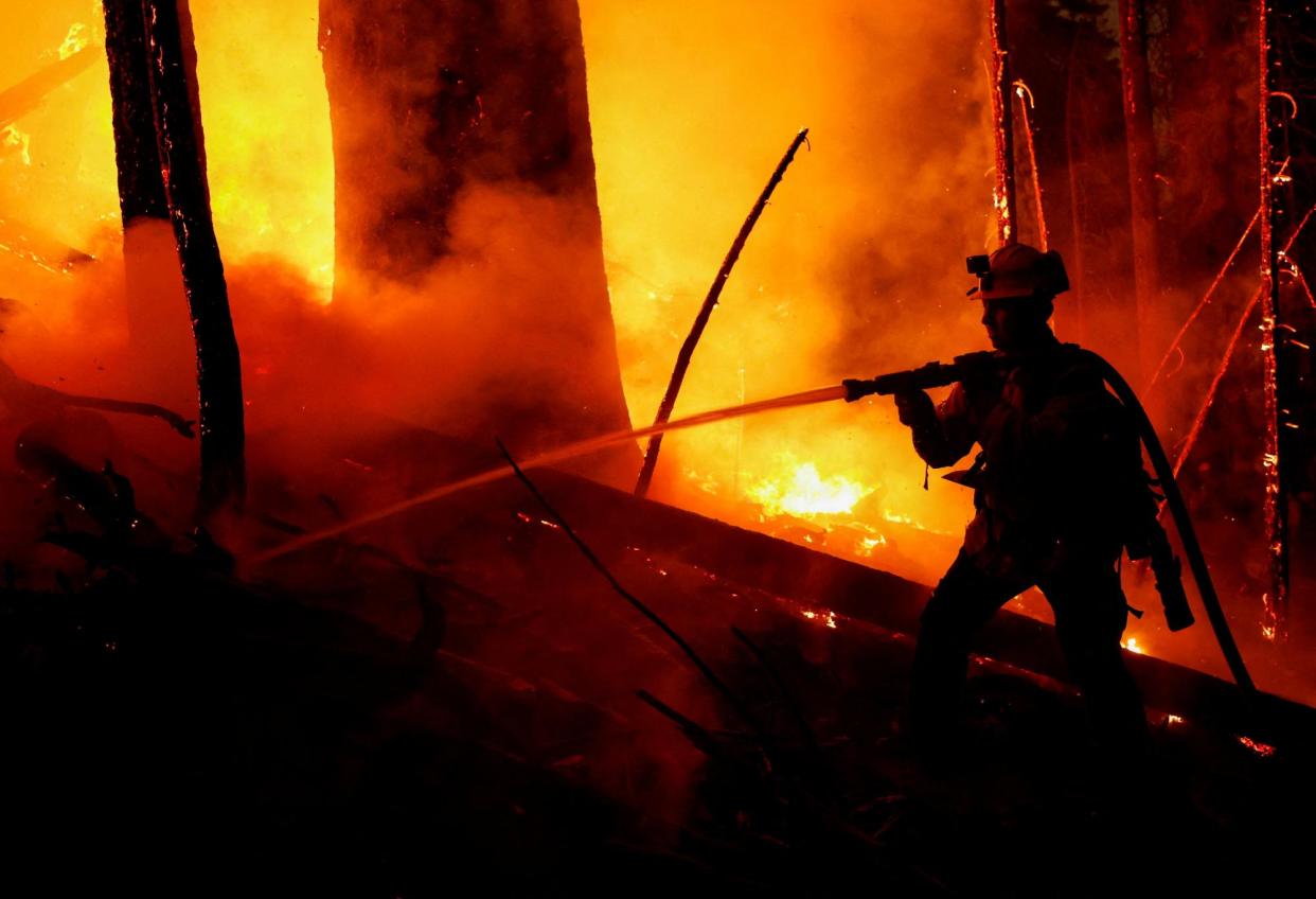 <span>A firefighter works to extinguish a spot fire from the Park Fire near Mill Creek, California, on 7 August.</span><span>Photograph: Fred Greaves/Reuters</span>