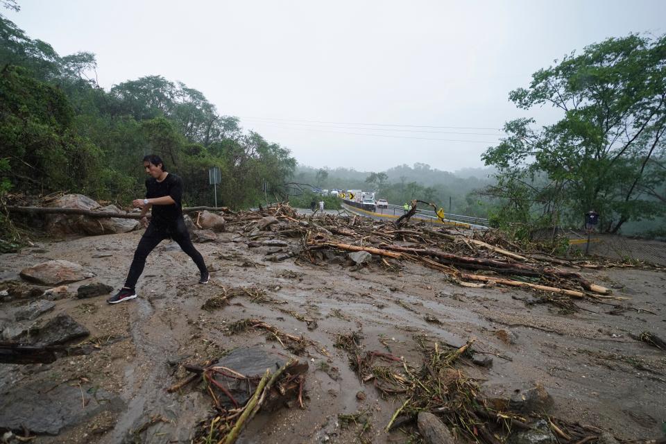 A man crosses a highway blocked by a landslide triggered by Hurricane Otis near Acapulco, Mexico, Wednesday, Oct. 25, 2023 (AP)