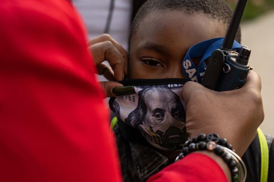 Thirkell Elementary-Middle School Principal Stephanie Gaines adjusts a student's mask at the end of the school day in Detroit on Friday, Nov. 13, 2020.