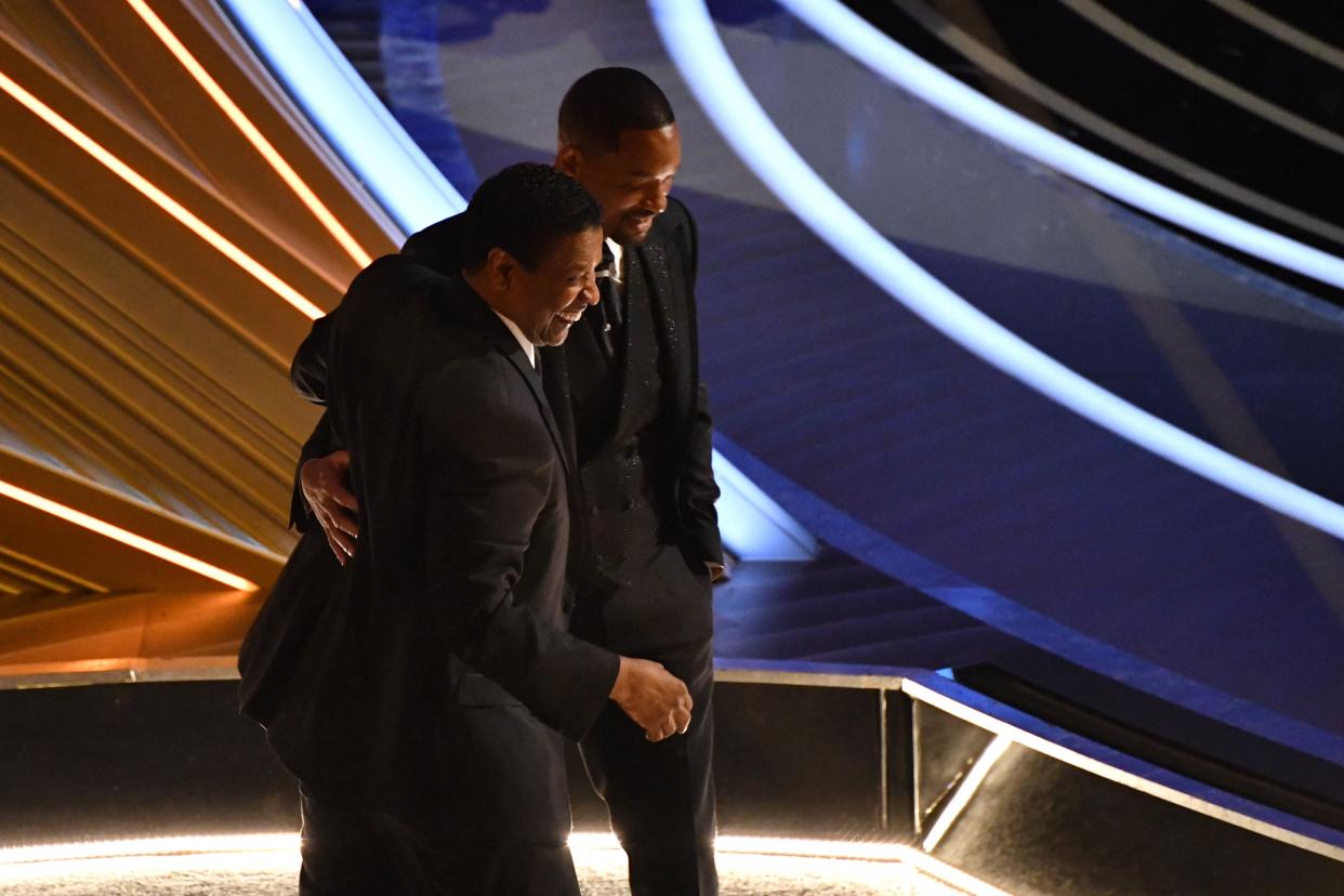 Denzel Washington and Will Smith smile and talk at the 2022 Oscars