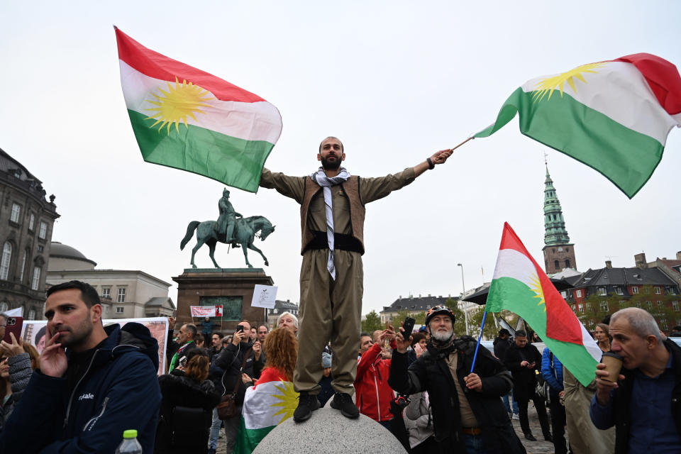 A protestor waves two Iranian flags.