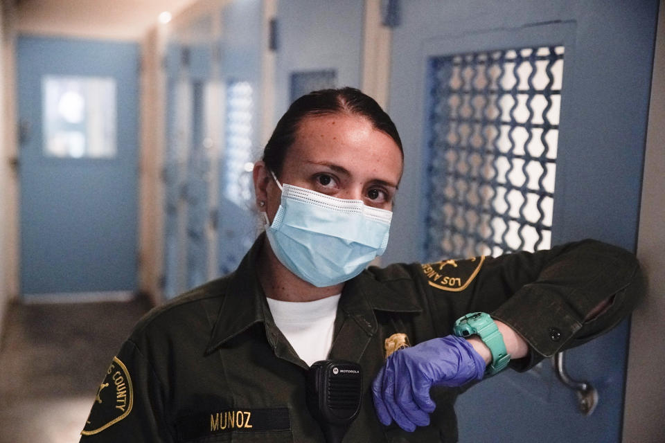 In this April 16, 2020, photo Sonia Munoz, a custody assistant, poses for a picture at the hospital ward of the Twin Towers jail in Los Angeles. Across the country first responders who've fallen ill from COVID-19, recovered have begun the harrowing experience of returning to jobs that put them back on the front lines of America's fight against the novel coronavirus. (AP Photo/Chris Carlson)