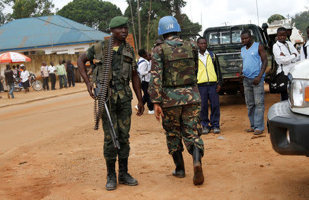 FILE PHOTO: A peacekeeper serving in the United Nations Organization Stabilization Mission in the Democratic Republic of the Congo (MONUSCO) and a Congolese soldier stand guard as residents gather following recent demonstrations in Beni in North Kivu province, Congo on October 23, 2014. REUTERS/Kenny Katombe/File Photo