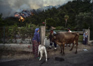 People leave with their animals as advancing fires rage Hisaronu area, Turkey, Monday, Aug. 2, 2021. For the sixth straight day, Turkish firefighters battled Monday to control the blazes that are tearing through forests near Turkey's beach destinations. Fed by strong winds and scorching temperatures, the fires that began Wednesday have left eight people dead. Residents and tourists have fled vacation resorts in flotillas of small boats or convoys of cars and trucks.(AP Photo)