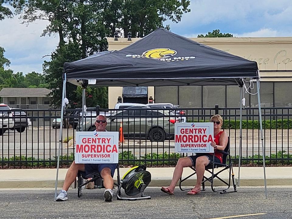 Supporters of Forrest County District 1 supervisor candidate Gentry Mordica hold up signs as motorists pass by outside Hardy Street Baptist Church precinct.