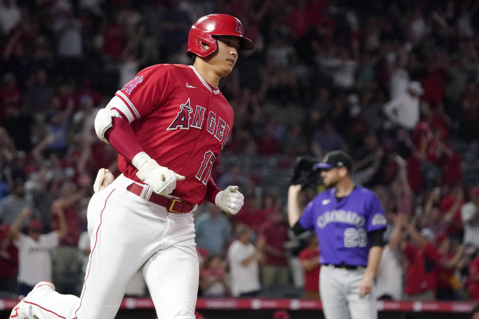 Los Angeles Angels' Shohei Ohtani, left, rounds first after hitting a two-run home run as Colorado Rockies starting pitcher Austin Gomber waits for another ball during the sixth inning of a baseball game Tuesday, July 27, 2021, in Anaheim, Calif. (AP Photo/Mark J. Terrill)