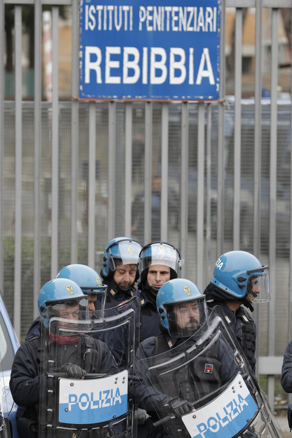 Police stand in front of the entrance of Rebibbia prison's after inmates staged a protest against new coronavirus containment measures, in Rome, Monday, March 9, 2020. Italian penitentiary police say six inmates protesting coronavirus containment measures at the northern Italian prison of Modena have died after they broke into the infirmary and overdosed on methadone. The protest Sunday in Modena was among the first of more than two-dozen riots at Italy's overcrowded lock-ups that grew Monday. (AP Photo/Andrew Medichini)