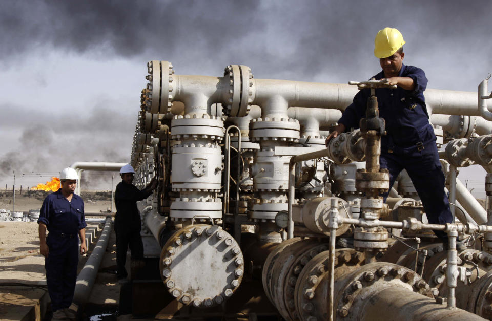 FILE - In this Dec. 13, 2009 file photo, men work at the Rumaila oil refinery, near the Iraqi city of Basra. Iraq is rich in oil, but protesters say they don’t see the fruits of this wealth. Fueling the unrest is anger over an economy flush with oil money that has failed to bring jobs or improvements to the lives of young people, who are the majority of those taking to the streets. (AP Photo/Nabil al-Jurani, File)