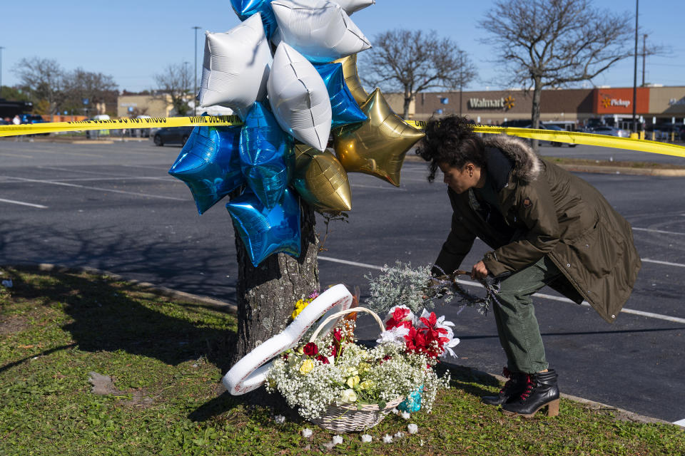 Shyleana Sausedo-Day, from Portsmouth, Va., places flowers near the scene of a mass shooting at a Walmart, Wednesday, Nov. 23, 2022, in Chesapeake, Va. A Walmart manager opened fire on fellow employees in the break room of the Virginia store, killing several people in the country’s second high-profile mass shooting in four days, police and witnesses said Wednesday. (AP Photo/Alex Brandon)