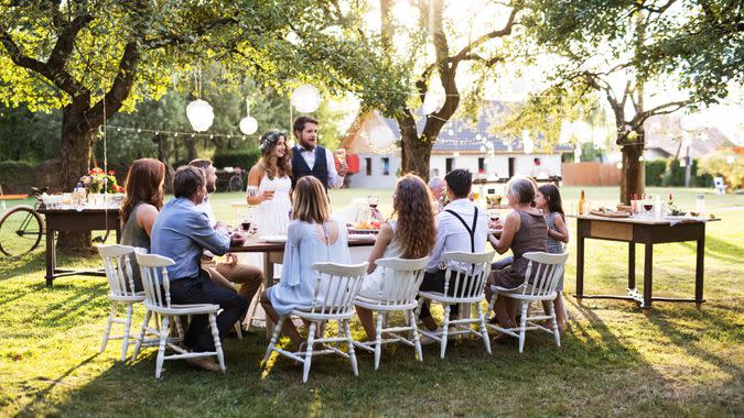 Bride and groom with guests at wedding reception outside in the backyard