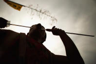 PHUKET, THAILAND - OCTOBER 05: A devotee of the Chinese shrine of Sui Boon Tong Shrine, pierces his cheek with a sword during a procession of Vegetarian Festival on October 5, 2011 in Phuket, Thailand. Ritual Vegetarianism in Phuket Island traces it roots back to the early 1800's. The festival begins on the first evening of the ninth lunar month and lasts for nine days. Participants in the festival perform acts of body piercing as a means of shifting evil spirits from individuals onto themselves and bring the community good luck. (Photo by Athit Perawongmetha/Getty Images)