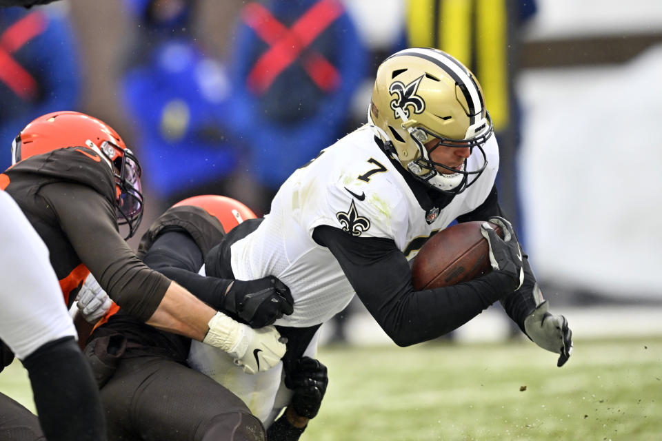 New Orleans Saints tight end Taysom Hill (7) carries Cleveland Browns defenders into the end zone for an 8-yard rushing touchdown during the second half of an NFL football game, Saturday, Dec. 24, 2022, in Cleveland. (AP Photo/David Richard)