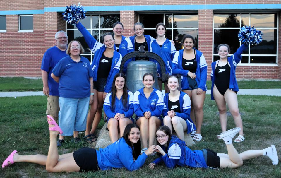 Members of the Perry swim team pose for a photo by the victory bell after defeating Algona on Thursday, Aug. 24, 2023.