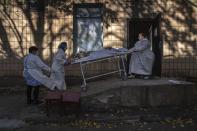 FILE - In this Friday, Oct. 22, 2021 file photo, medical stuff transport a body of a patient who died of coronavirus at morgue of the city hospital 1 in Rivne, 300 kilometers (190 miles) west of Kyiv, Ukraine. Ukraine is suffering through a surge in coronavirus infections, along with other parts of Eastern Europe and Russia. While vaccines are plentiful, there is a widespread reluctance to get them in many countries — though notable exceptions include the Baltic nations, Poland, the Czech Republic, Slovenia and Hungary. (AP Photo/Evgeniy Maloletka, File)