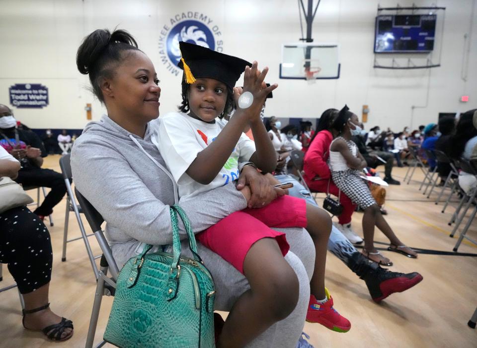 Milwaukee Academy of Science rising first grader Nathaniel Logan claps while sitting on the lap of his mother, Ayanna Taylor, as they get the news of the "I Have A Dream" scholarship program during a K-5 promotion ceremony Thursday.
