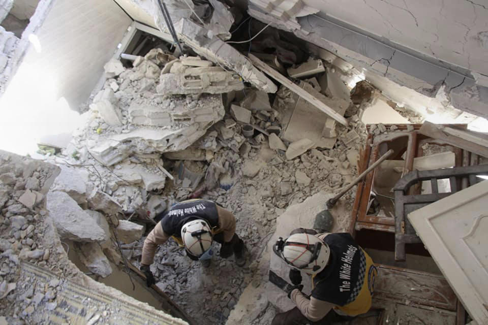 This photo posted on Tuesday, May 28, 2019 and provided by the Syrian Civil Defense White Helmets, which has been authenticated based on its contents and other AP reporting, shows Civil Defense workers searching for victims under the rubble of a destroyed building after an airstrike by Syrian government forces, in the town of Ariha, in the northwestern province of Idlib, Syria. Syrian activists and rescuers say government warplanes and artillery have pounded the last rebel stronghold in the country, killing over a dozen people. (Syrian Civil Defense White Helmets via AP)