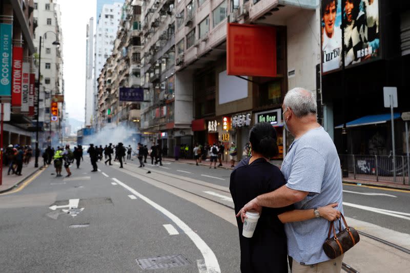 Couple hug each other as police fire tear gas into the crowds to disperse anti-national security law protesters during a march at the anniversary of Hong Kong's handover to China from Britain in Hong Kong