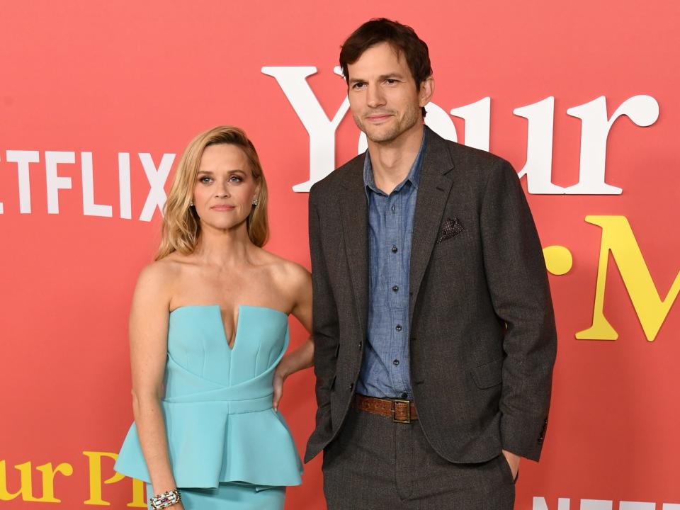 reese witherspoon and ashton kutcher at the your place or mine premiere. they're standing next to each other but not really posing together — witherspoon has her hand resting on her hip, while kutcher is standing a respectable distance away with his hands in his pockets