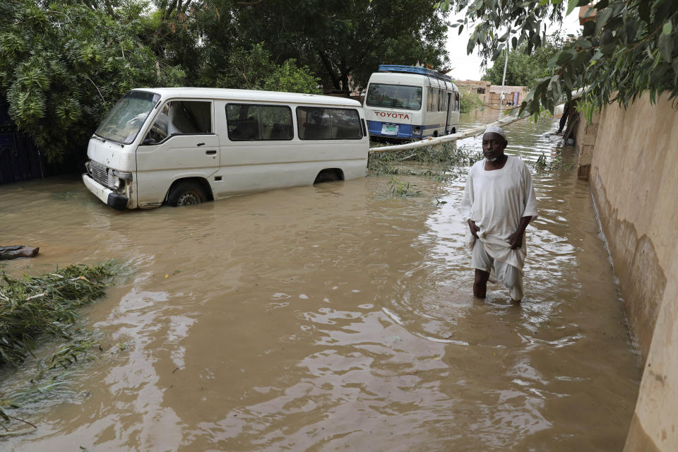 A man wades through a flooded road in the town of Shaqilab, about 15 miles (25 km) southwest of the capital, Khartoum, Sudan, Monday, Aug. 31, 2020. (AP Photo/Marwan Ali)