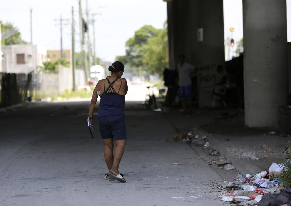 In this Wednesday, July 24, 2019 photo, Ivette Naida walks down a Miami street after receiving her HIV medication from social workers from the IDEA Exchange. Naida is participating in the University of Miami-sponsored program, which provides HIV-infected homeless people with secure medication lockers or delivers small quantities of medicine to them directly. Naida, who was diagnosed with HIV more than a decade ago, lives underneath a Miami highway overpass and has no safe place to keep her belongings. (AP Photo/Lynne Sladky)