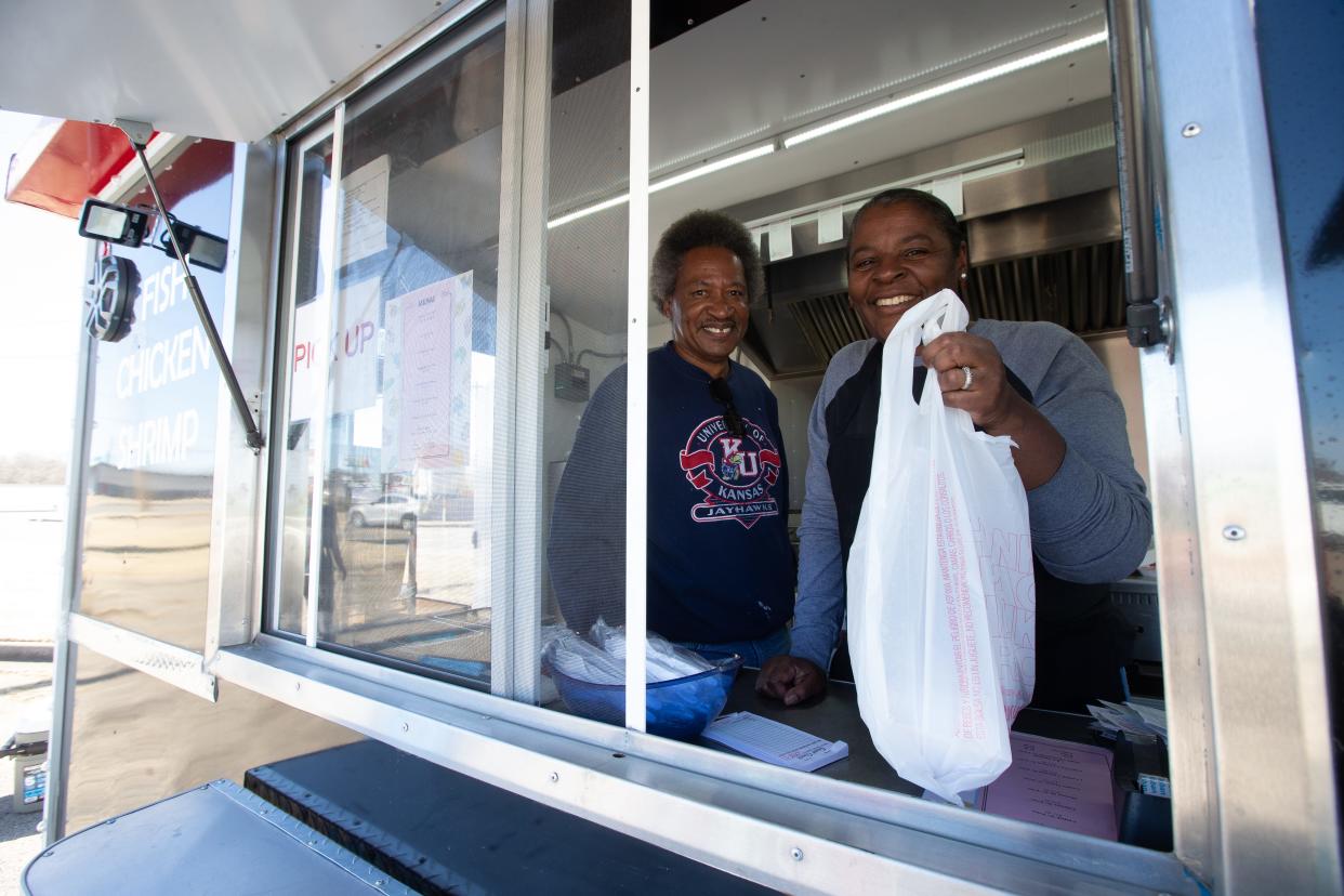 Owners of Hook & Que food truck, Millie and John McMurray, hand out a customer's order Monday afternoon. The food truck was Monday's featured restaurant for the Topeka Black Restaurant and Food Truck Week.