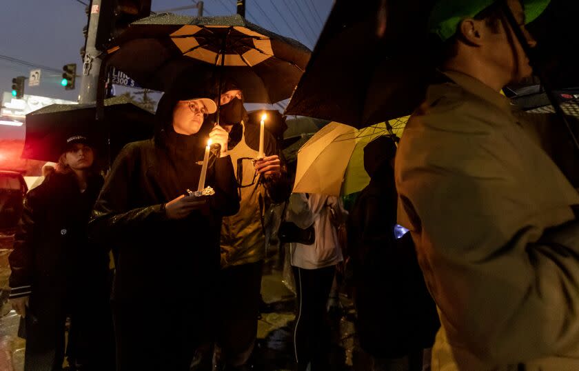 VENICE, CA - JANUARY 14, 2023: Ann Marie Slocum and Sean Uren of Los Angeles huddle together under an umbrella during a rain storm to attend the vigil for Keenan Anderson who was killed after being tased by LAPD following a traffic collision earlier this month January 14, 2023 in Venice, California. (Gina Ferazzi / Los Angeles Times)