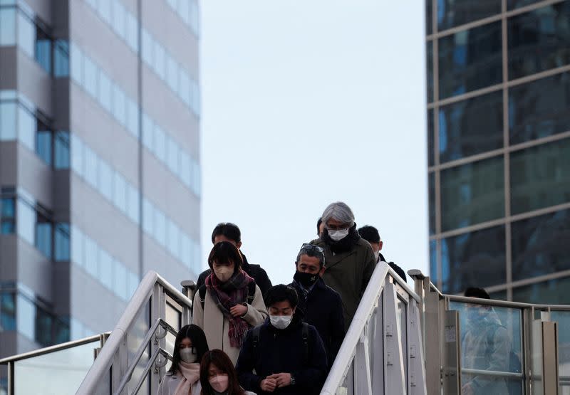 Commuters wearing protective face masks amid the COVID-19 pandemic make their way at a train station in Tokyo