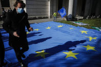 FILE - in this Wednesday, April 22, 2020 file photo, a man with a face mask and a child with an European flag attend an event of the Pulse of Europe movement to collect signatures for more support for Italy during the coronavirus and the COVID-19 outbreak in front of the Italian embassy in Berlin, Germany. European Union leaders are preparing for a new virtual summit, which will take place Thursday, April 23, 2020, to take stock of the damage the coronavirus has inflicted on the lives and livelihoods of the bloc's citizens and to thrash out a more robust plan to revive their ravaged economies. (AP Photo/Markus Schreiber, File)