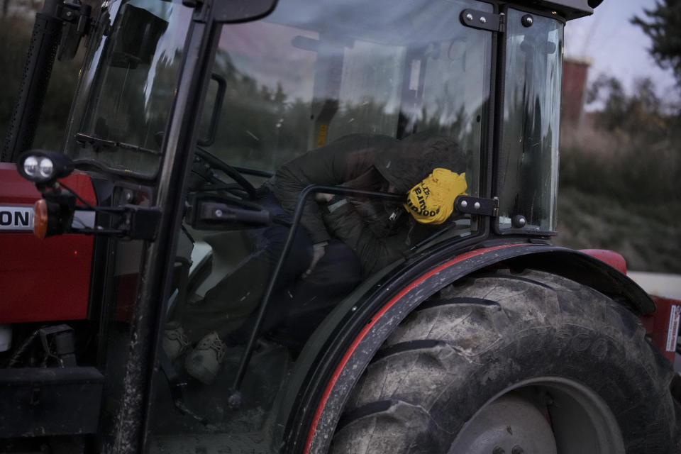 A farmer sleeps in their tractor after spending night at a highway barricade in Aix-en-Provence, southern France, Tuesday, Jan. 30, 2024. France's protesting farmers encircled Paris with traffic-snarling barricades Monday, using hundreds of lumbering tractors and mounds of hay bales to block highways leading to France's capital to pressure the government over the future of their industry. (AP Photo/Daniel Cole)