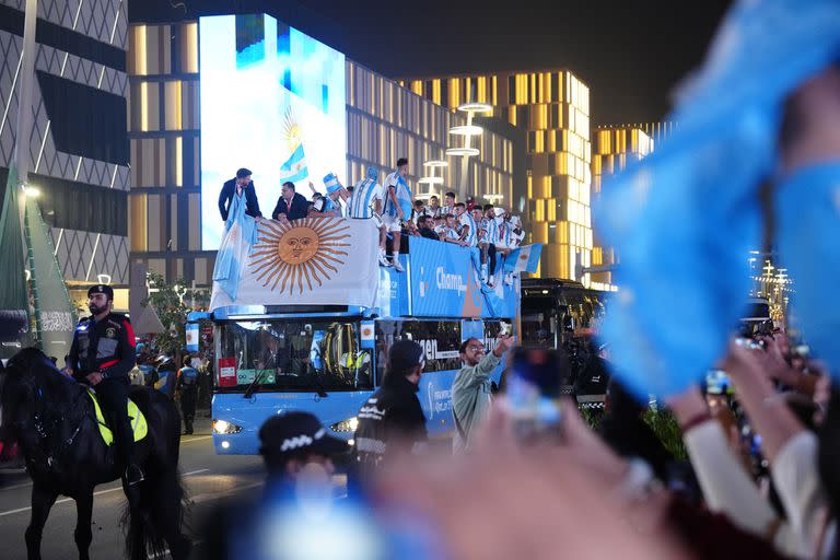 A bus with the celebrating Argentine players who wave to their fans travels from the Lusail Stadium after they won the World Cup Final defeating France on penalties, in Lusail, Qatar, Monday Dec. 19, 2022. The match was played Sunday Dec. 18. (AP Photo/Pavel Golovkin)