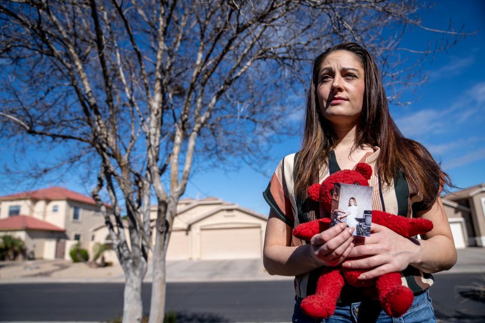 Kimber Biggs poses for a portrait as she holds a photograph of her sister Mikelle Biggs and Mikelle's teddy bear, at her home in Gilbert on Jan. 25, 2024. Mikelle Biggs, who was 11 years old, disappeared while riding her bike near her home in Mesa on Jan. 2, 1999.