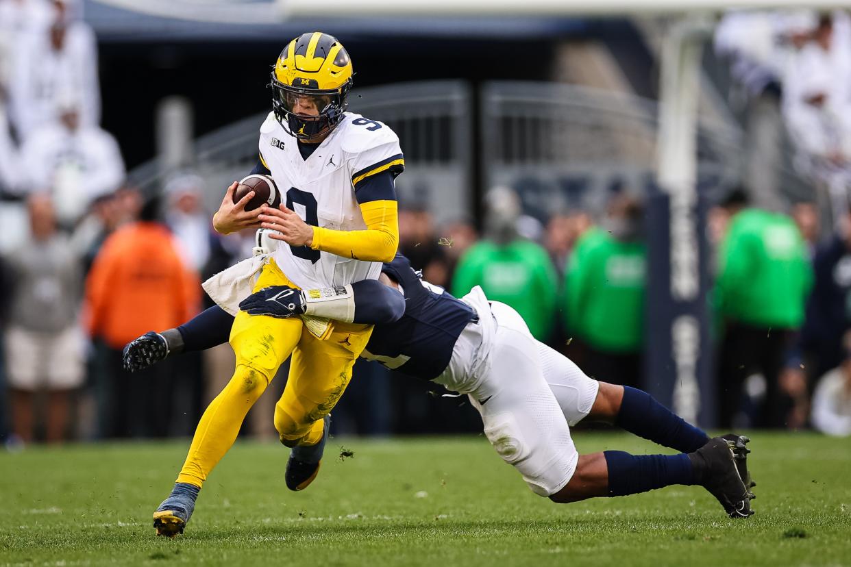 J.J. McCarthy of the Michigan Wolverines carries the ball as Kobe King of the Penn State Nittany Lions defends during the second half at Beaver Stadium on November 11, 2023 in State College, Pennsylvania.