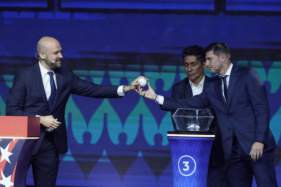 Javier Zanetti, former Argentine soccer player, right, handles over a ball with a draw outcome to Carlos Fernandez, Director of Competitions at CONCACAF, during the draw for the Copa America soccer tournament, Thursday, Dec. 7, 2023, in Miami. The 16-nation tournament will be played in 14 U.S. cities starting with Argentina's opener in Atlanta on June 20, 2024. (AP Photo/Lynne Sladky)