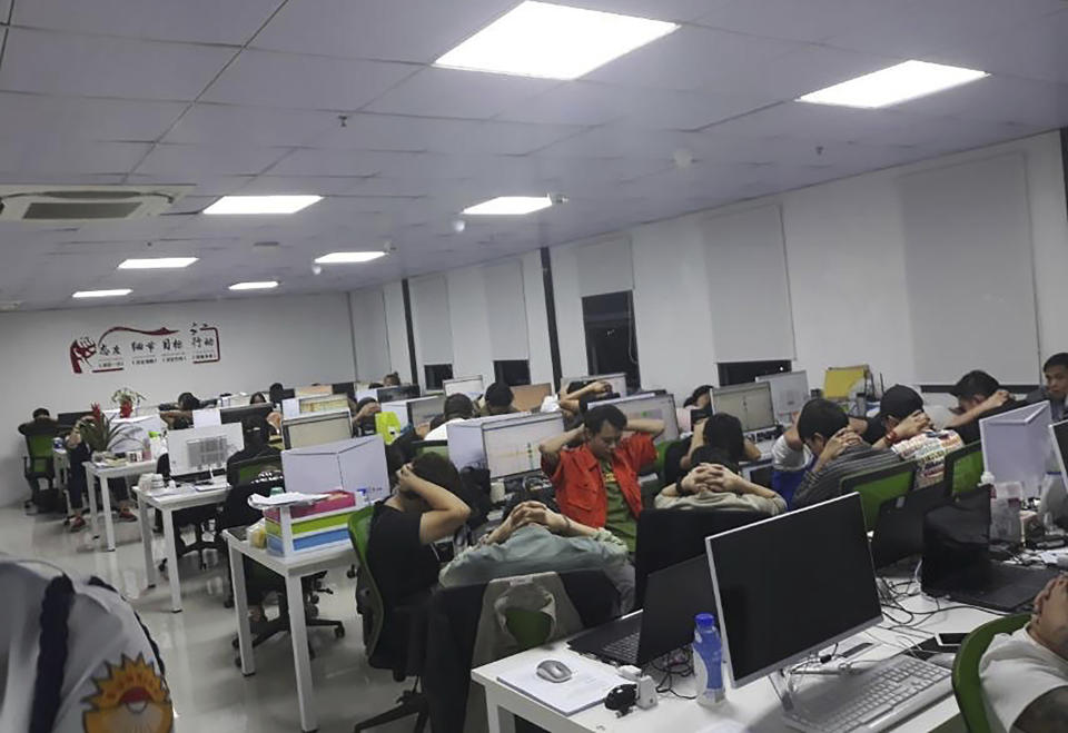 In this Oct. 9, 2019, photo provided by Philippine Bureau of Immigration, foreign nationals, mostly Chinese put their hands on their heads during a raid of their company premises in Manila, Philippines. Philippine police and immigration authorities said they have arrested more than 500 illegally working foreigners, mostly Chinese involved in telecommunications and investment scams, in one of the biggest such mass arrests this year. (Philippine Bureau of Immigration Via AP)