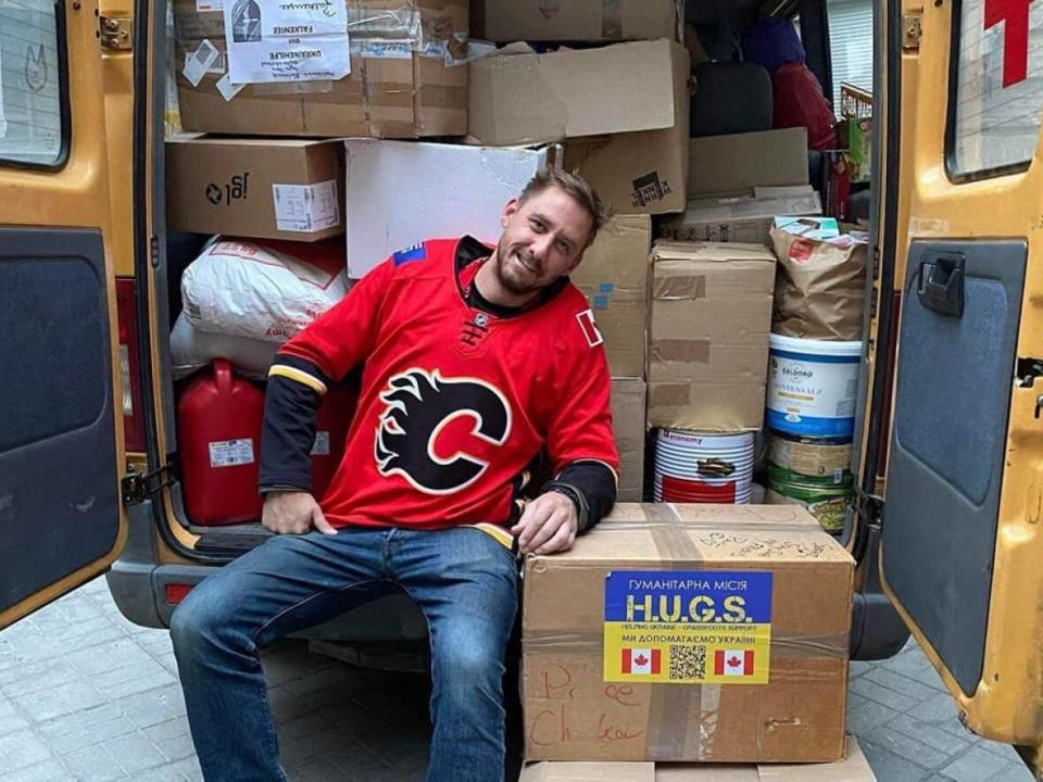 Steve Rock, 34, is a volunteer in Ukraine. He wears his Flames jersey to lift his spirits as he follows the team's playoff progress from afar.  (Supplied by HUGS - image credit)