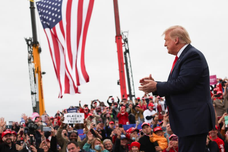 El presidente de EEUU Donald Trump aplaude a su llegada a un evento de campaña en el aeropuerto internacional de MBS, en Freeland