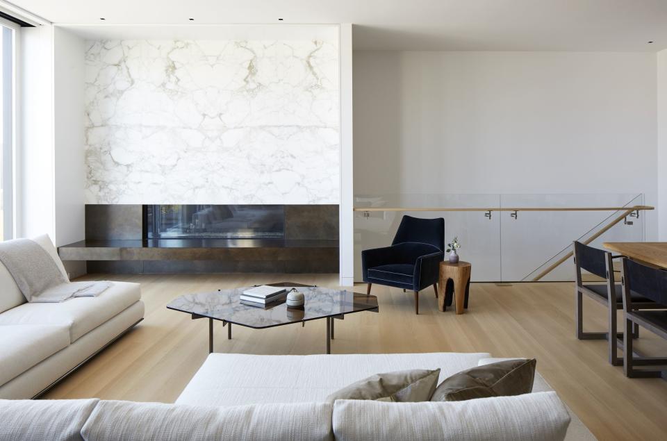 With its wall of glass pocket doors that slide open to an outdoor deck facing San Francisco Bay, designer Catherine Kwong could afford to keep her client's living room clean and simple. A white linen Minotti sectional and navy mohair chair are accented by a smoked glass coffee table from Egg Collective and a stunning slab of Calacatta D’oro marble above the fireplace.