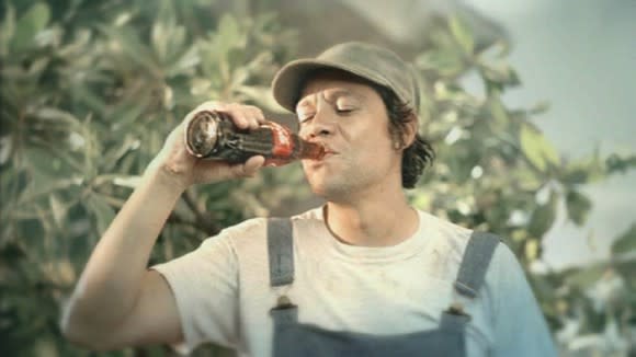 A field worker taking a sip of Coca-Cola from the bottle.