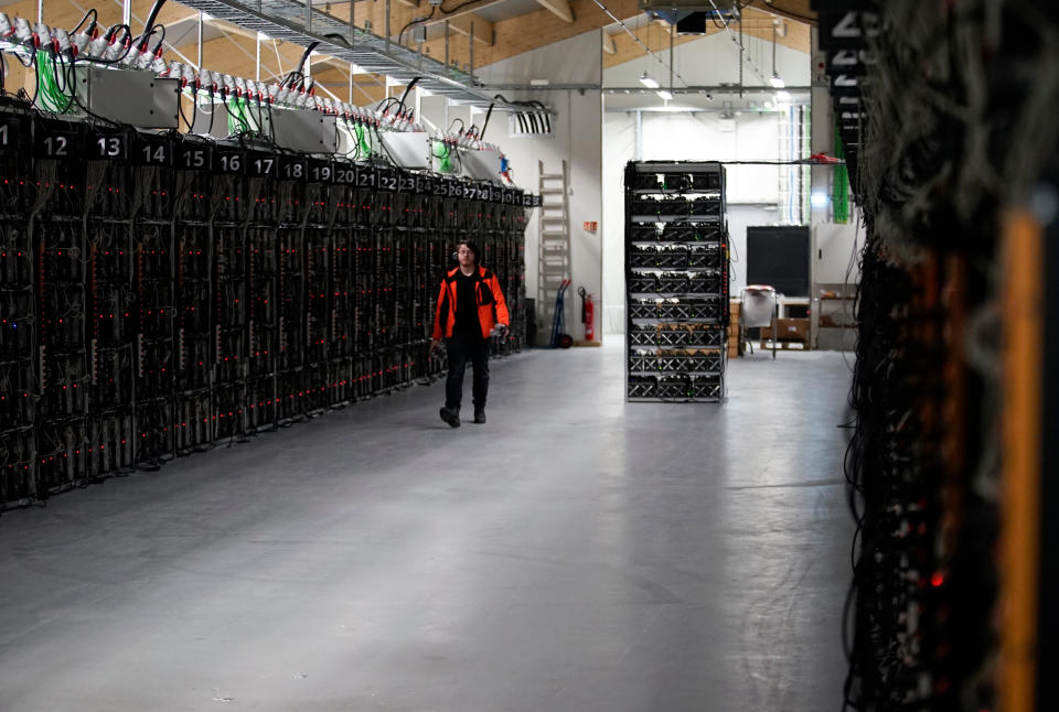 In this photo taken on January 17, 2018, inside the Genesis Mining cryptocurrency mine in Iceland, a man walks along a row of computer rigs that run around the clock 'mining' bitcoin. At the edge of the Arctic, bitcoin miners seek natural cooling and competitive prices for Icelandâs abundance of renewable energy. (AP Photos/Egill Bjarnason)