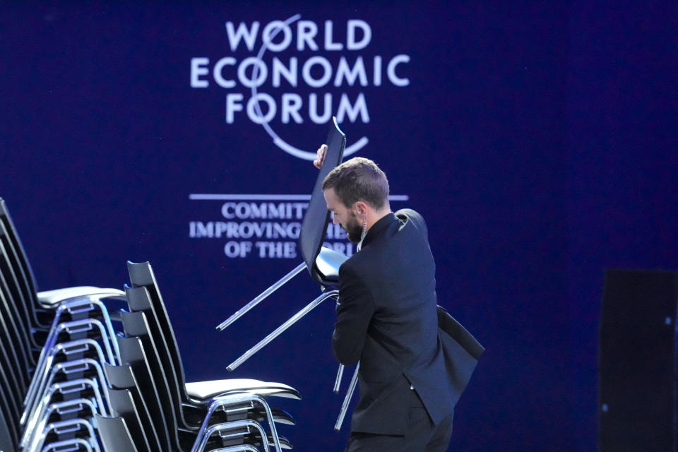 A man stacks chairs during cleanup in the congress hall after the World Economic Forum in Davos, Switzerland Friday, Jan. 20, 2023. The annual meeting of the World Economic Forum is taking place in Davos from Jan. 16 until Jan. 20, 2023. (AP Photo/Markus Schreiber)