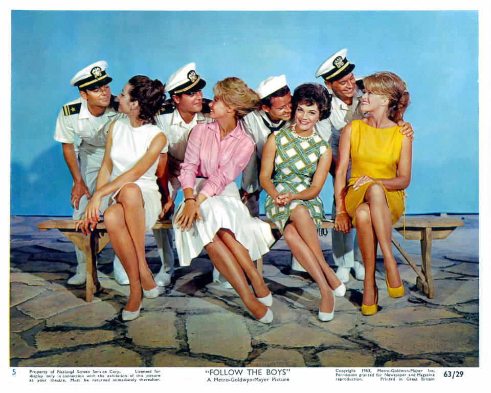 Paula Prentiss, Yvette Mimieux, Connie Francis and Dolores Hart sitting on a bench together with four men dressed in military uniforms standing behind them flirting for their attention in a scene from the film 'Where the Boys Are', 1960. (Photo by Metro-Goldwyn-Mayer/Getty Images)