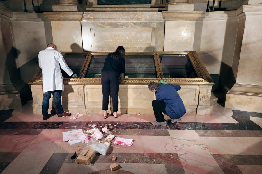 National Archives employees clean pink powder on the casement of the U.S. Constitution inside the National Archives Rotunda in Washington, Feb. 14, 2024. The National Archives building and galleries were evacuated after two protesters dumped powder on the protective casing around the U.S. Constitution. (William J. Bosanko/National Archives via AP)