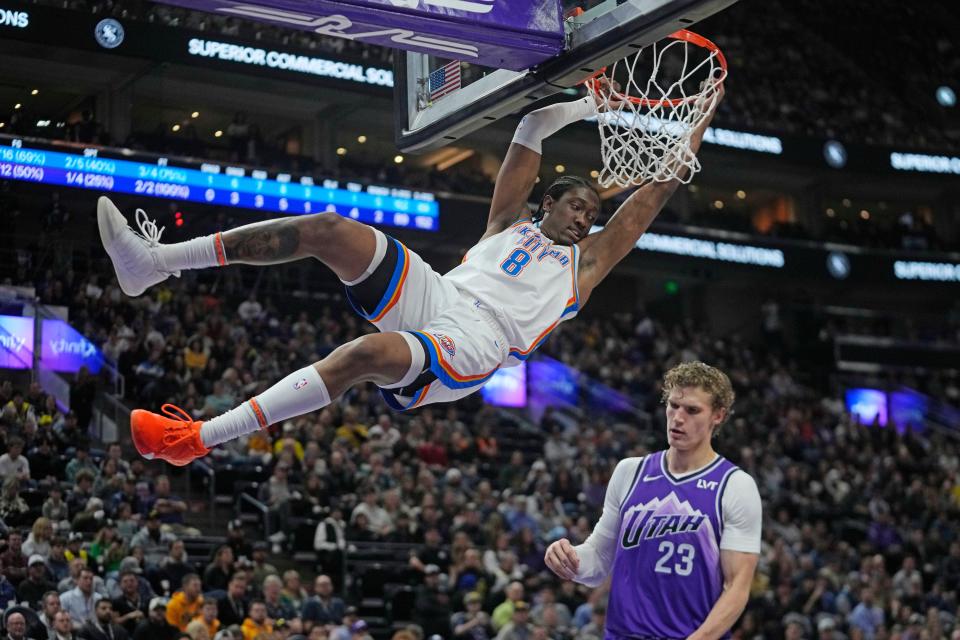 Thunder forward Jalen Williams (8) holds on to the rim after dunking against Jazz forward Lauri Markkanen (23) on Jan. 18 in Salt Lake City.