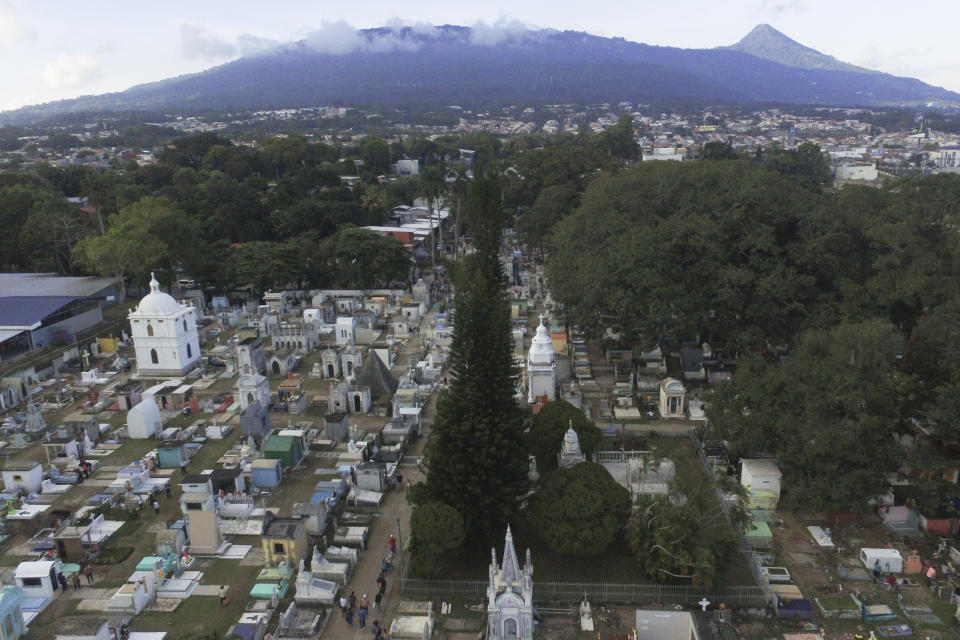 General view of the Nueva San Salvador Cemetery, with the San Salvador volcano in the background, during the Day of the Dead celebrations in Santa Tecla, El Salvador, Wednesday, Nov. 2, 2022. Santa Tecla Mayor Henry Flores said the crews had destroyed nearly 80 tombstones in the municipal cemetery and erased gang-related graffiti. (AP Photo/Salvador Melendez)